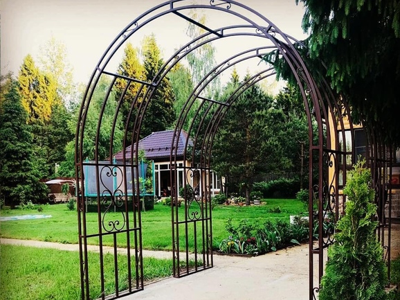 Кованая садовая арка над тропинкой с завитками