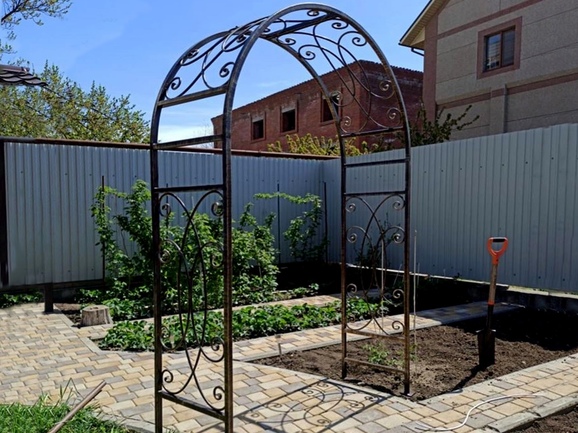 Садовая кованая арка с завитками на дорожке